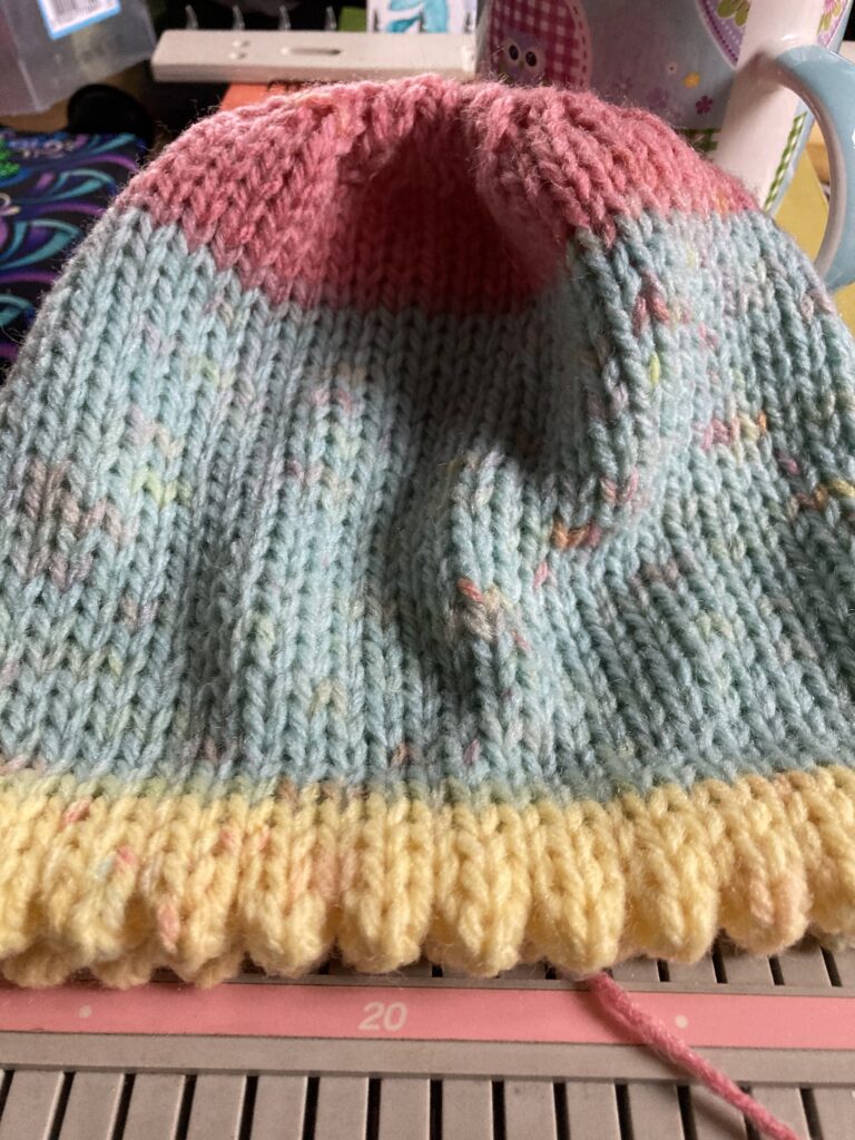 completed hat laying on the knitting machine bed